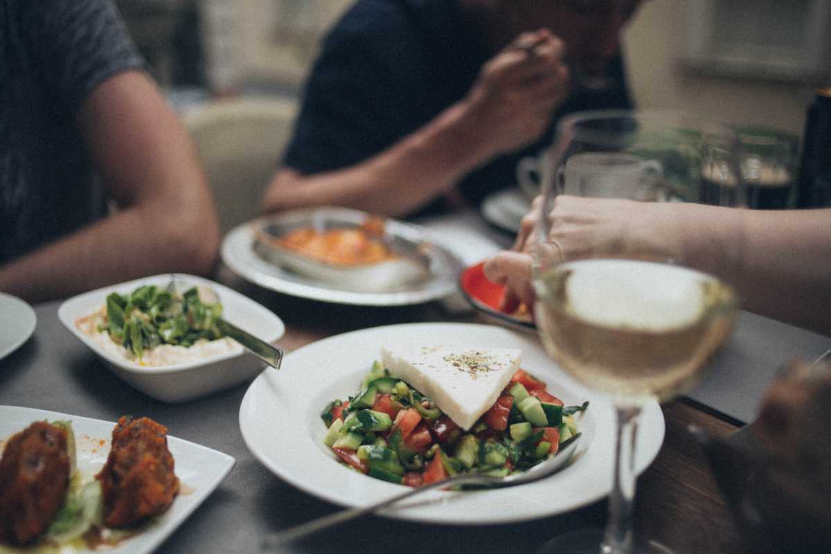 Dettaglio di un cuoppo di pesce fritto tra le mani di un turista in una via animata di Amalfi, atmosfera vivace, street food tipico